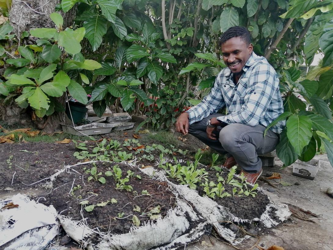 SOIL’s Director of Operations, Djimitri Célestin, growing directly out of Konpòs Lakay bags mixed with soil.